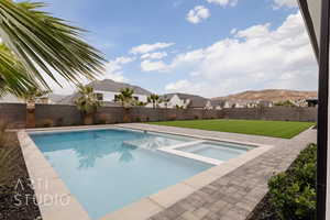 View of pool featuring a lawn, an in ground hot tub, and a mountain view