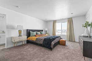 Bedroom featuring ensuite bath, light carpet, and a textured ceiling