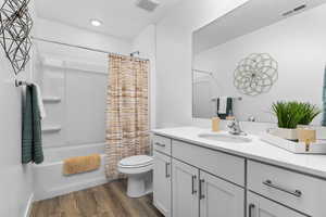 Full bathroom with hardwood / wood-style flooring, shower / bath combo, toilet, and vanity