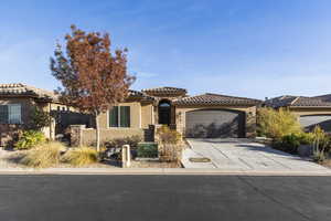 View of front of house with stucco siding, a tiled roof, a garage, driveway, and stone siding
