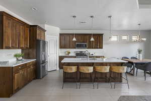 Kitchen featuring a center island with sink, sink, hanging light fixtures, stainless steel appliances, and a chandelier