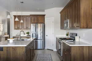 Kitchen with pendant lighting, a kitchen island with sink, sink, light tile patterned floors, and appliances with stainless steel finishes