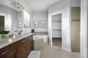 Bathroom with tile patterned floors, vanity, and tiled tub