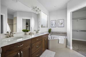 Bathroom featuring vanity, tile patterned flooring, and tiled tub