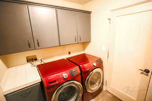 Washroom featuring washing machine and clothes dryer and cabinets