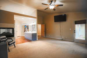 Carpeted living room featuring ceiling fan, lofted ceiling, and sink