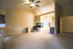 Unfurnished living room with ceiling fan, lofted ceiling, and light carpet