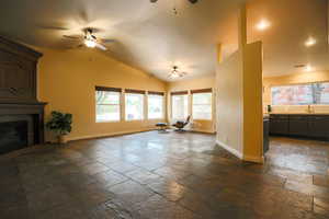 Unfurnished living room with ceiling fan, a fireplace, vaulted ceiling, and sink