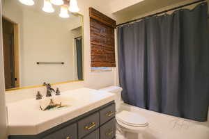 Full bathroom featuring shower / bath combination with curtain, vanity, toilet, and tile patterned floors