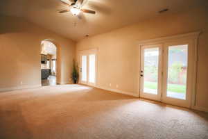 Unfurnished living room with ceiling fan, carpet floors, and vaulted ceiling