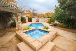 View of pool with an in ground hot tub and a patio