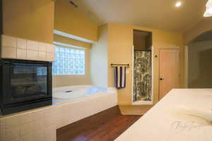 Bathroom with hardwood / wood-style floors, separate shower and tub, lofted ceiling, and sink