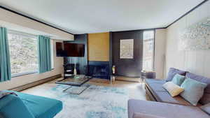 Living room with baseboard heating, a wealth of natural light, and a large fireplace