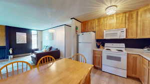 Kitchen featuring white appliances, decorative light fixtures, light hardwood / wood-style flooring, and baseboard heating