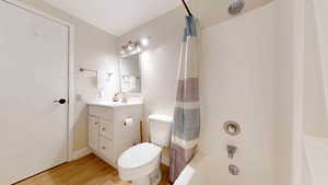 Full bathroom featuring shower / bath combo, toilet, wood-type flooring, and vanity