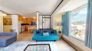 Living room featuring light hardwood / wood-style flooring, baseboard heating, and a healthy amount of sunlight