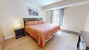 Bedroom with baseboard heating and light hardwood / wood-style floors