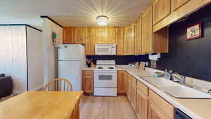 Kitchen with sink, white appliances, and light wood-type flooring