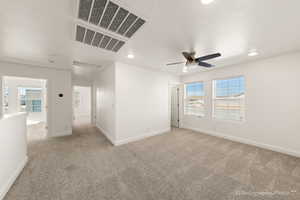 Carpeted spare room featuring ceiling fan, a healthy amount of sunlight, and a textured ceiling