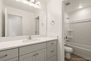 Full bathroom with shower / tub combination, vanity, wood-type flooring, and toilet