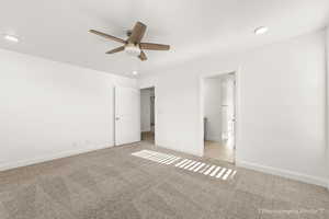 Unfurnished bedroom with a walk in closet, light colored carpet, and ceiling fan