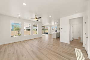 Unfurnished living room with ceiling fan, a healthy amount of sunlight, and light hardwood / wood-style floors