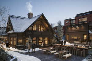 Snow covered back of property with a wooden deck