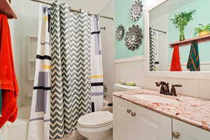 Full bathroom with shower / tub combo with curtain, vanity, and toilet