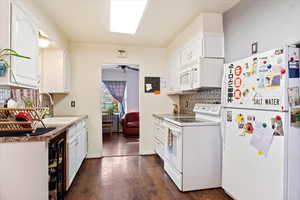 Kitchen featuring white cabinetry, sink, dark hardwood / wood-style floors, and white appliances