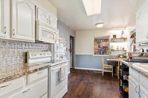 Kitchen featuring decorative backsplash, light stone counters, white appliances, dark hardwood / wood-style floors, and white cabinetry