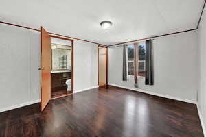 Unfurnished bedroom with hardwood / wood-style flooring, sink, a textured ceiling, and ensuite bath