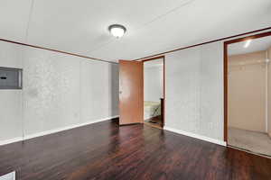 Unfurnished bedroom with ensuite bathroom, a textured ceiling, dark wood-type flooring, electric panel, and a closet