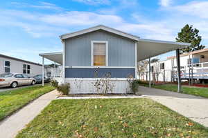 View of side of home with a lawn and a carport