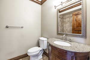 Bathroom with tile patterned floors, ornamental molding, a tile shower, vanity, and toilet