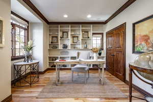 Office space with ornamental molding, a healthy amount of sunlight, and light hardwood / wood-style floors