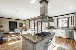 Kitchen with island range hood, white cabinetry, and stainless steel appliances