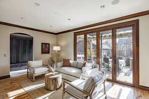 Living room with crown molding, light hardwood / wood-style flooring, and french doors