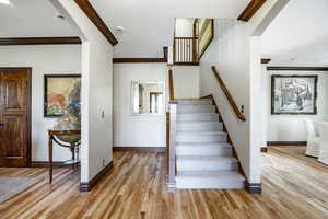 Stairs with hardwood / wood-style flooring and crown molding