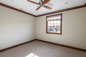 Carpeted empty room with ceiling fan and ornamental molding