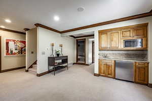 Kitchen featuring decorative backsplash, light colored carpet, ornamental molding, and stainless steel appliances