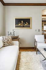 Living room with ornamental molding and light hardwood / wood-style flooring