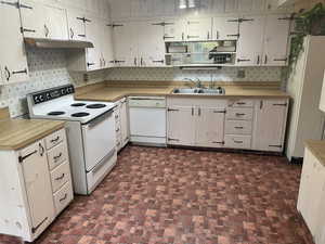 Kitchen with decorative backsplash, sink, and white appliances