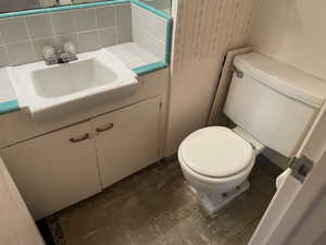 Bathroom with decorative backsplash, vanity, and toilet