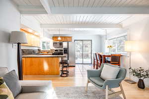 Living room featuring beam ceiling, light wood-type flooring, and wooden ceiling