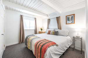 Carpeted bedroom featuring beam ceiling and wooden ceiling