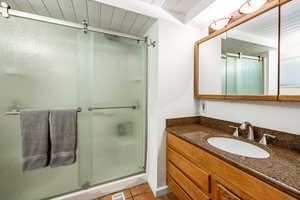 Bathroom featuring wooden ceiling, tile patterned flooring, vanity, and a shower with shower door