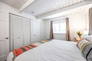 Bedroom with beamed ceiling, a closet, and wood ceiling