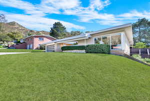 Ranch-style house with a mountain view and a front lawn