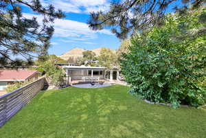 Back of property with a lawn, a mountain view, and a patio area