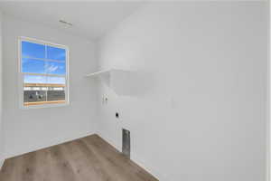 Laundry room with hookup for an electric dryer, hookup for a washing machine, and light wood-type flooring